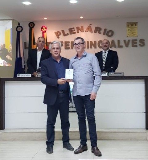 Prefeito Cilon Rodrigues da Silveira entrega a homenagem ao Diretor da Escola Major João Antônio Marques, Sr. Davenir Oliveira.