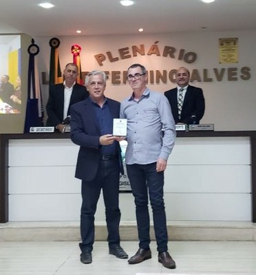 Prefeito Cilon Rodrigues da Silveira entrega a homenagem ao Diretor da Escola Major João Antônio Marques, Sr. Davenir Oliveira.